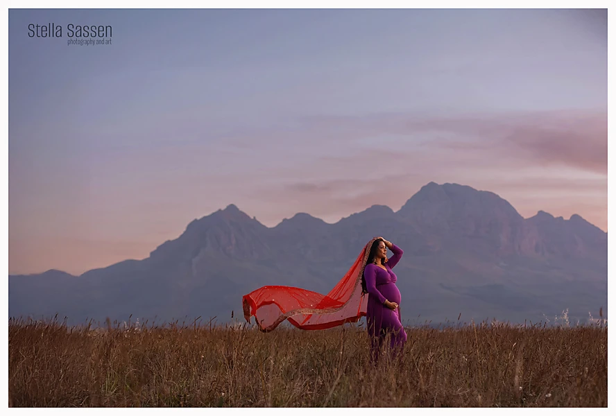 maternity photo of woman in field with mountain background and indian veil